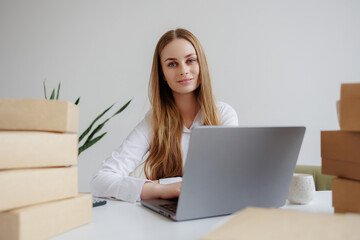 Young woman working in a bright workspace surrounded by cardboard boxes during daytime