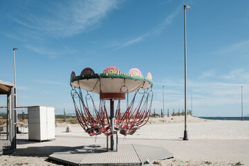 Abandoned carousel on the beach under a blue sky