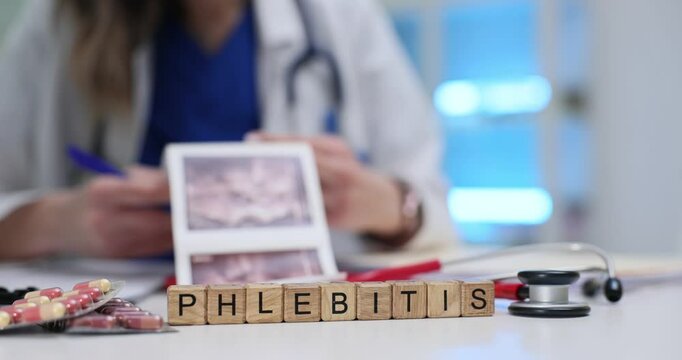 Medical doctor holds ultrasound scan examining picture near Phlebitis diagnosis on wooden cubes. Treatment by healthcare professional in clinic