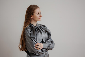 Elegant woman in grey blouse poses thoughtfully against neutral backdrop in a minimalist studio...