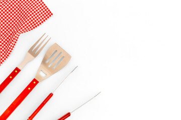 Stainless steel utensils and red picnic napkin, top view. Barbecue utensils
