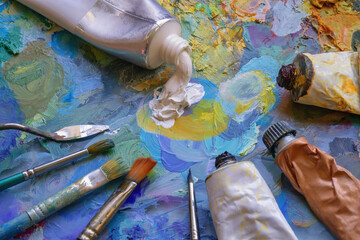 Palette with different oil paints, tubes and paintbrushes
