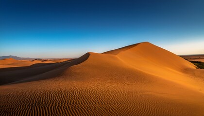 golden sand dune stands majestic against a clear blue sky