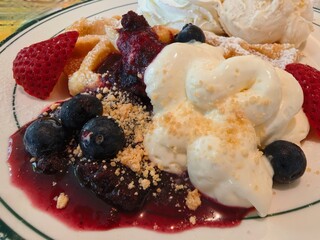 Delicious waffles topped with fresh berries, cream, and sauce.