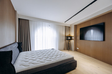 A cozy bedroom with a comfy mattress and a wallmounted TV