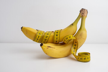 Yellow banana with measuring tape on light background.
Weight loss concept. Men's health concept.