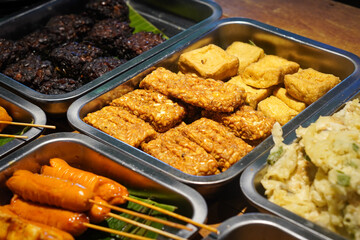 Assorted Side Dishes, Indonesia, captured on May 29, 2025. A variety of traditional Indonesian foods including tempeh, tofu, chicken, eggs, and vegetables served with sambal