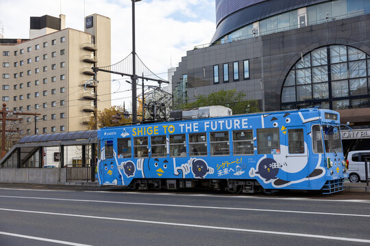 Okayama City, Japan - December 2024: Wide view of the urban area in front of Okayama Station, the central transportation hub of. The scene includes city buildings, local buses, trams, and pedestrians 