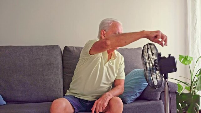 Video of Elderly man sweating and suffering from summer heat using an electric fan
