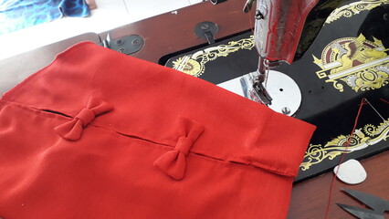 a red shirt that has been finished in sewing and folded neatly on a sewing machine