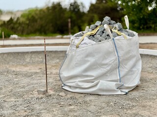 Big white bag full of granite cubes at a construction site. Stones are prepared for paving or...
