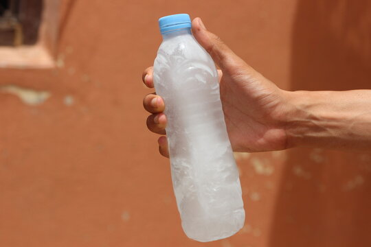 Hand holding a bottle of frozen water
