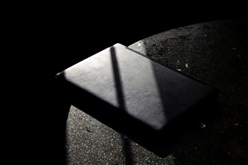 A grey laptop on a dark, textured surface, dramatically highlighted by a sharp beam of light and...