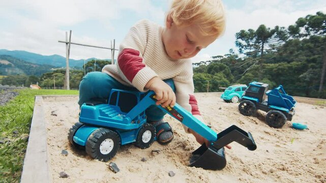 Boy plays with toys in the sand on the outdoor playground