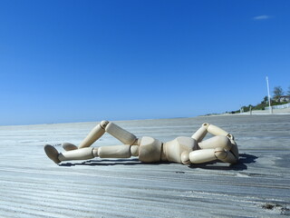 wooden manikin portraying a person who chills on the beach