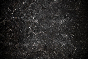 Black water with ripples. Defocus blurred black clear calm water surface texture with splashes and...