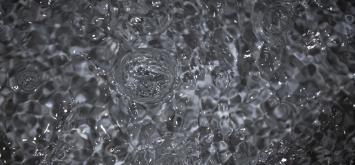 Black water with ripples. Defocus blurred black clear calm water surface texture with splashes and...