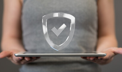 Image of a person holding a tablet with a digital shield and checkmark, representing data security...