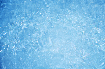 Blue water with ripples. Defocus blurred bleu clear calm water surface texture with splashes and bubbles.