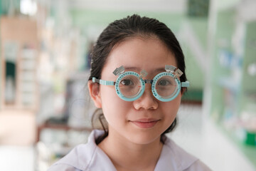 Cute Thai Girl Undergoing Eye Exam with Pediatric Trial Frame