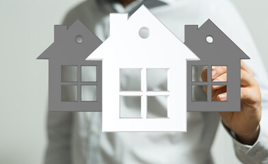Image of a real estate agent holding three house icons, representing home buying, selling, or...