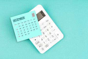 December 2025 calendar card with calculator on blue background.