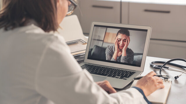 Female psychologist calms down emotional crying woman patient by video call on computer