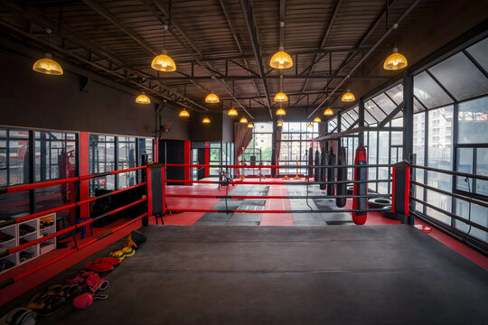 Spacious, well-lit boxing gym featuring a red ring, punching bags, gloves, and fitness gear&mdash;ideal for sports, fitness, or healthy lifestyle content