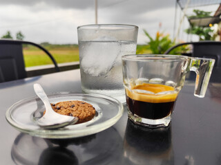 A cup of hot black coffee with other accompaniments, served in a natural themed cafe.