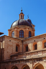 The Ducale Palace, an iconic symbol of Urbino, highlights intricate brickwork and elegant domes. This architectural marvel reflects the city's rich history. Urbino, Marche, Italy