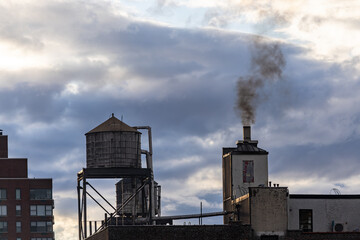 New York, New York, USA A residential house, a rooftop water tank, and a smokestack with smoke.