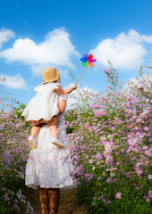 Cute mother and little daughter in a flower field,Happy mother with little daughter on lavender background. Beautiful woman and cute baby playing in meadow field. Family holiday in summer day.