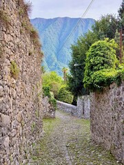 Old stone alleyways in Lenno and Ossuccio, Italy, featuring cobbled paths, rustic walls, olive trees and lush greenery, offering a peaceful atmosphere in a charming lakeside village