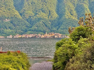 Peaceful lakeside promenade in Lenno and Ossuccio, with neatly trimmed trees, waterfront benches, mountain views, colorful villages and scenic perspectives over Lake Como