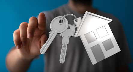 Person holding keys with house icon.  Real estate, homeownership, new home concept.