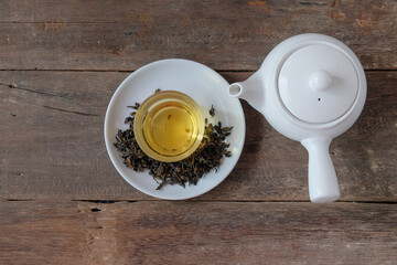 White Tea pot and cups of hot beverage on wooden.