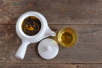 White Tea pot and cups of hot beverage on wooden.