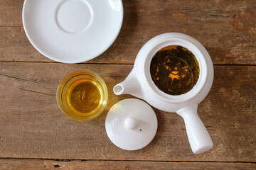 White Tea pot and cups of hot beverage on wooden.