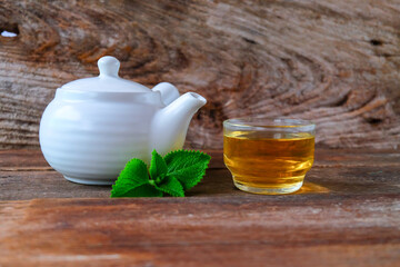White Tea pot and cups of hot beverage on wooden.