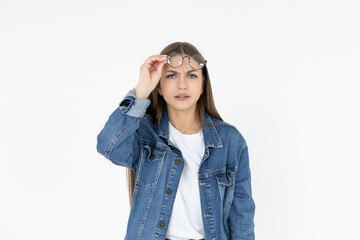 Fototapeta premium I dont believe you. A close-up portrait of a shocked girl, amazed woman with open mouth and big eyes, she touches glasses in surprise expression over white backdrop. People emotions.