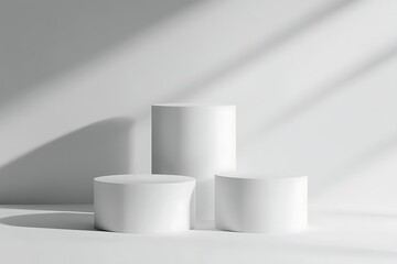 Three simple, white, cylindrical display stands arranged in a modern, minimalist setting against a light gray background