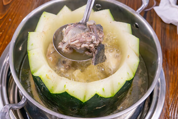 taking out soft-shelled turtle slices from a boiling winter melon soup to cook