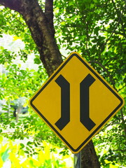 Yellow traffic sign attached on pole in public park, Traffic Sign square shape, with a black bridge on a yellow background. Narrow Bridge Ahead warning sign means that there is a narrow bridge ahead, 