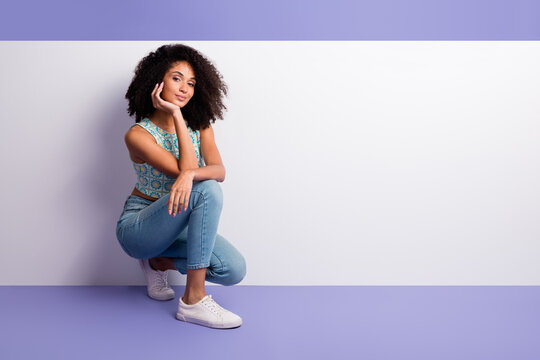 Trendy young woman in casual outfit seated against vibrant purple background, showcasing stylish summer fashion