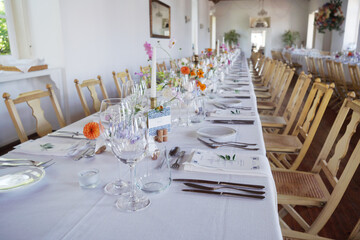Banquet table in rustic European style. White tablecloth and empty glasses and plates..