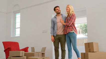 Excited Young Couple Looking Around New Home On Moving Day Together