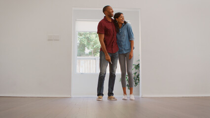 Excited Young Couple Looking Around New Home On Moving Day Together
