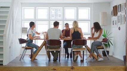 Group Of Friends Sitting Around Table Enjoying Dinner Party At Home Together