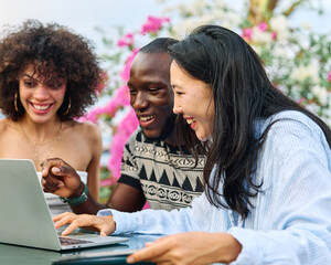 Portrait of group of young people hangout in the city , sitting in a coffee shop or bar table using a laptop together and having fun.