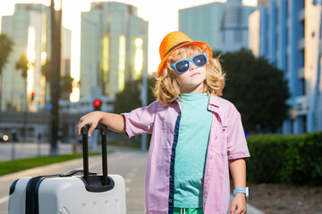 Child traveler with suitcase outdoor. Tourist kid boy having cheerful holiday trip. Child travel...